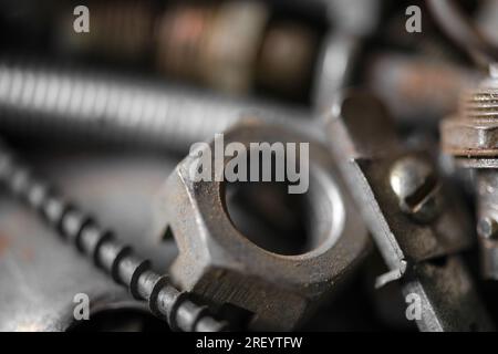 Boulons, rouages et autres pièces sont en désordre dans le garage, atelier de réparation. Fête de papa. Macrophotographie. Banque D'Images