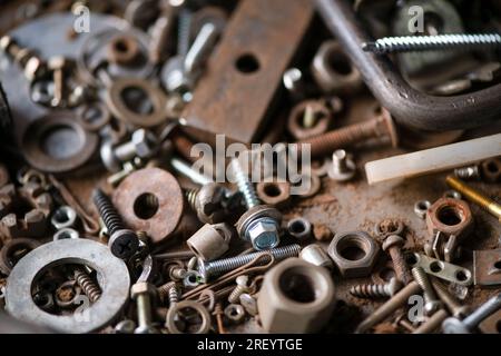 Boulons, rouages et autres pièces sont en désordre dans le garage, atelier de réparation. Fête de papa. Macrophotographie. Banque D'Images