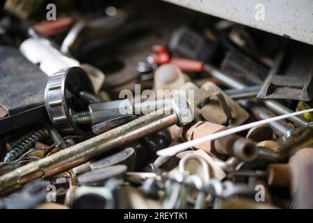 Boulons, rouages et autres pièces sont en désordre dans le garage, atelier de réparation. Fête de papa. Macrophotographie. Banque D'Images