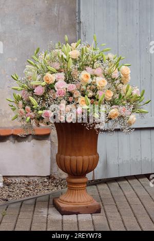 Bouquet luxueux de roses, lys et gypsophila dans un grand vase classique. Banque D'Images