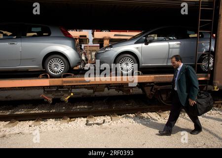 Un conducteur de train marchant à l'avant de son train de marchandises transportant de nouvelles voitures, Trenitalia, le système ferroviaire national italien, 2005 Banque D'Images