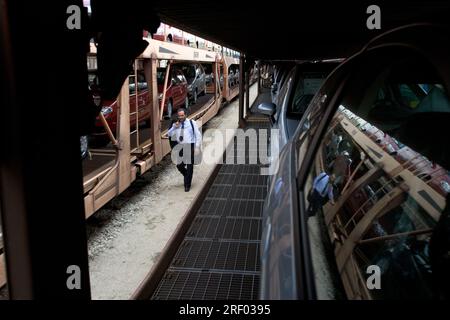 Un conducteur de train marchant à l'avant de son train de marchandises transportant de nouvelles voitures, Trenitalia, le système ferroviaire national italien, 2005 Banque D'Images