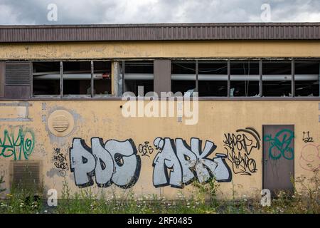 Graffitis et étiquettes sur le mur d'un bâtiment industriel abandonné et vandalisé à Paimio, Finlande Banque D'Images