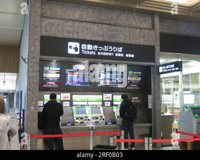 Deux passagers masculins se tiennent devant le distributeur automatique de billets à la gare de Kanazawa au Japon Banque D'Images