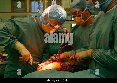 Equipe médicale pratiquant une chirurgie de prothèse de hanche en salle d'opération hospitalière. Banque D'Images