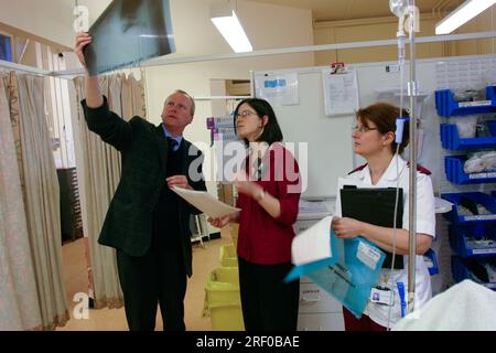 Personnel médical examinant une radiographie dans un environnement hospitalier, y compris un médecin et deux infirmières discutant de l'image. Banque D'Images