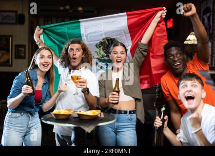 Joyeux fans de l'équipe mexicaine célébrant la victoire au bar de nuit Banque D'Images