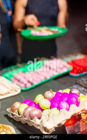 A côté de toute une variété colorée d'autres snacks, à un marché de nuit de nourriture à Dumaguete, près de la zone piétonne populaire et mur de mer, beaucoup de brochettes ke Banque D'Images