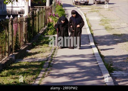 Comté de Neamt, Roumanie, 1999. Vieille nonne marchant sur la route avec une aide. Banque D'Images