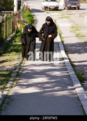 Comté de Neamt, Roumanie, 1999. Vieille nonne marchant sur la route avec une aide. Banque D'Images