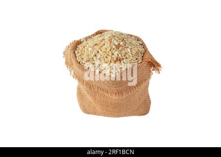 Grain de riz brun dans le sac en toile de jute isolé sur blanc. Céréales crues, crues, à grains entiers. Banque D'Images