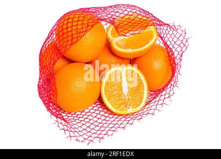 Oranges fraîches et juteuses dans un sac de maille rouge de détail isolé sur fond blanc. Une orange est coupée en deux. Banque D'Images