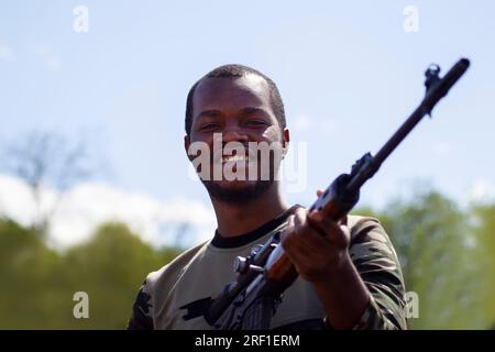 .Un homme noir tient un fusil de sniper et sourit. Banque D'Images