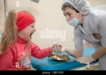 Les mains du médecin pansent le doigt douloureux avec un bandage de l'enfant. Blessure et blessure Banque D'Images