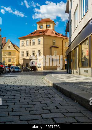 Rue pavée et maison typique avec toit rouge sous ciel bleu dans la vieille ville de Prague, République tchèque. Banque D'Images