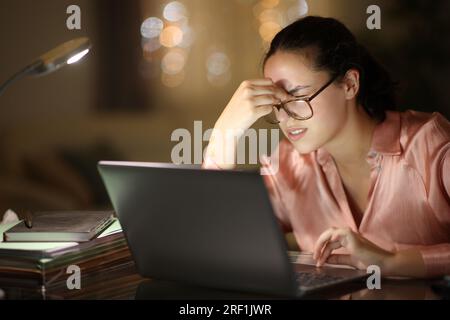 Entrepreneur portant des lunettes de travail souffrant de fatigue oculaire dans la nuit à la maison Banque D'Images