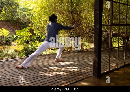Homme indien concentré pratiquant le yoga sur la terrasse ensoleillée Banque D'Images