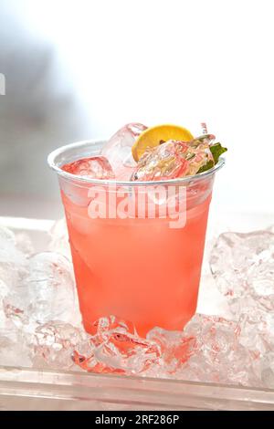Limonade rose posée sur des glaçons avec une tranche de citron et de la menthe fraîche. Banque D'Images