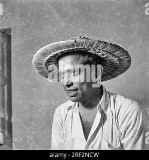 Vieux vintage des années 1900 noir et blanc portrait studio de l'homme indien portant chapeau de paille casquette chemise Inde des années 1940 Banque D'Images