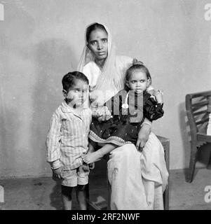 Vieux vintage des années 1900 photo en noir et blanc de studio de famille indienne portrait femme assise portant sari fils fille Inde des années 1940 Banque D'Images