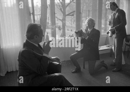 PHOTO D’ARCHIVE : Andy WARHOL aurait eu 95 ans le 6 août 2023, ART/politique Andy WARHOL(r.), USA, artiste, Représentation de l'ex-chancelier Willy BRANDT (SPD) avec une caméra instantanée. Warhol est agenouillé sur une jambe, tenant la caméra vers le haut, mais ne regarde pas à travers elle, semblant plutôt donner des instructions à Brandt. Brandt est assis sur une chaise et tient une cigarette avec un embout buccal dans sa main droite, demi-longueur de profil et plutôt silhouette, mais toujours reconnaissable. Warhol peut être vu dans une figure complète de face. Photo noir et blanc, format paysage. ? Banque D'Images
