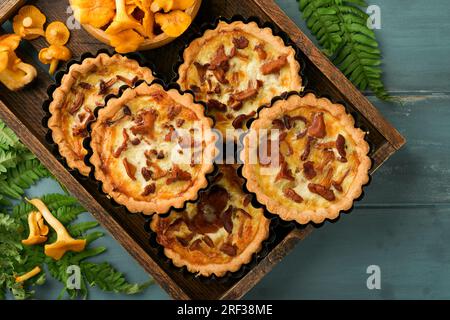 Tarte aux mains savoureuses avec des champignons chanterelles, crème et fromage sur une planche à découper sur fond de table en bois rustique. Tartes maison avec cha de saison Banque D'Images