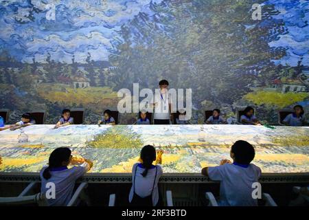 Tianjin, Chine. 30 juillet 2023. Les élèves regardent une exposition immersive d'une œuvre d'art au Musée d'art numérique de Tianjin, dans le nord de la Chine, le 30 juillet 2023. Pendant les vacances d'été, le Musée maritime national de Chine et le Musée d'art numérique de Tianjin ont offert conjointement aux étudiants un camp d'étude sur le thème de l'océan et de l'art. Au total, 22 étudiants de Pékin, Tianjin et de la province du Hebei ont appris des connaissances sur l’océan et la nature et sont entrés en contact avec l’art numérique pendant le camp. Crédit : Sun Fanyue/Xinhua/Alamy Live News Banque D'Images