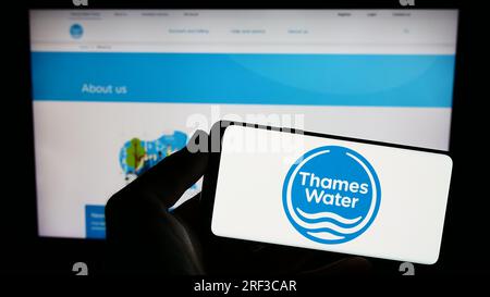 Personne tenant un smartphone avec le logo de la société britannique Thames Water Utilities Limited sur l'écran devant le site Web. Concentrez-vous sur l'affichage du téléphone. Banque D'Images