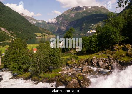 Vue sur Storfossen chute d'eau puissante jusqu'au fjord de Geiranger flanqué de montagnes couvertes d'arbres descend à plus de 35m de l'Hôtel Union à travers le village de Geiranger Banque D'Images