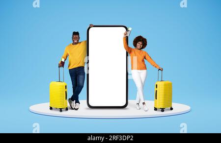 Heureux couple noir allant en vacances, debout près d'un énorme téléphone Banque D'Images