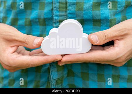 Homme tenant un petit symbole d'objet nuage blanc dans ses mains, gros plan. Cloud Server computing, puissance de traitement distribuée et service de stockage de fichiers Banque D'Images