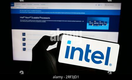 Personne tenant un smartphone avec le logo de la société technologique américaine Intel Corporation sur l'écran devant le site Web. Concentrez-vous sur l'affichage du téléphone. Banque D'Images