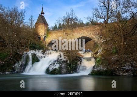 Moulin de Pyrmont en Rhénanie-Palatinat Allemagne Pont en pierre avec cascade un lac et maison à colombages. Un château en ruine en arrière-plan Banque D'Images