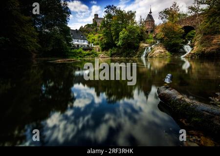 Moulin de Pyrmont en Rhénanie-Palatinat Allemagne Pont en pierre avec cascade un lac et maison à colombages. Un château en ruine en arrière-plan Banque D'Images