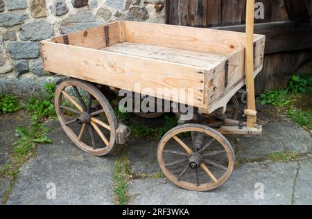 Vieux chariot en bois vide devant une grange agricole Banque D'Images