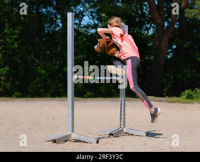 Fille sautant sur le cheval de passe-temps. Champion. Sport équestre. Lumière d'été. Fond vert des arbres extérieurs. Sport pour enfants. Bannière Banque D'Images