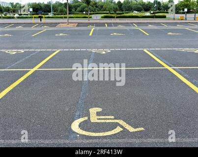 parking avec places de parking réservées aux personnes à mobilité réduite affichant le logo peint en orange sur le sol Banque D'Images