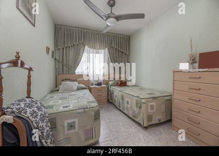 chambre avec lits jumeaux, couvre-lits à motifs verts, murs et rideaux de la même couleur Banque D'Images