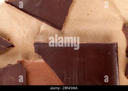 le lait et le chocolat amer se sont divisés en morceaux avec des miettes, plusieurs morceaux de chocolat cassé de différents types Banque D'Images