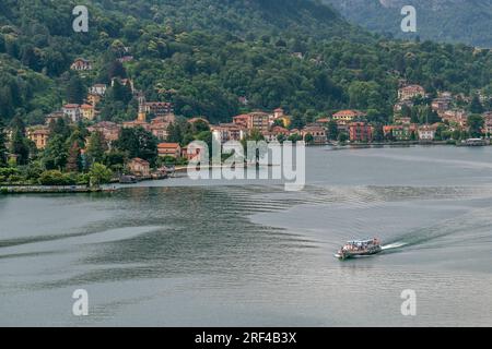 Vue aérienne panoramique de Porto Ceresio et du lac de Lugano, tandis qu'un bateau à moteur relie le côté italien au côté suisse Banque D'Images