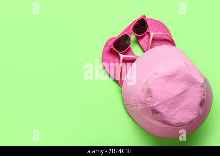 Tongs avec lunettes de soleil et chapeau de seau sur fond vert Banque D'Images