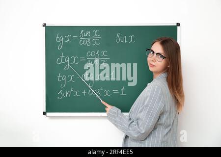 Jeune professeur de mathématiques avec pointeur près du tableau noir dans la salle de classe Banque D'Images