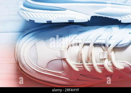 Vue de dessus des baskets blanches sur fond en bois avec lumière rouge et bleue. Banque D'Images