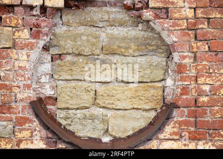 Vieux mur de briques avec fenêtre ronde barricadée, ancien fragment extérieur de l'église orthodoxe Banque D'Images