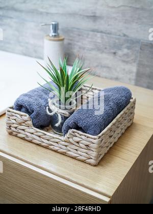 Panier avec des serviettes roulées propres empilées dans la salle de bains. Style écologique, nimalisme. Mise au point sélective. Banque D'Images