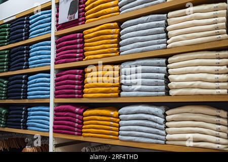 Vêtements chauds soigneusement pliés sur une étagère de magasin. Sweat-shirts, pulls, pulls, cardigans, hoodies.avec piles sur l'étagère Banque D'Images