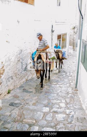 09-06-2018 Hydra, Grèce. Transport ecologicval dans la ville d'Hydra - ânes! Un homme monte sur un âne avec une charge et un deuxième homme marche à côté du Banque D'Images