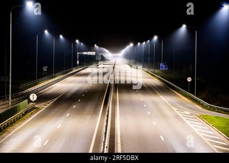 Autoroute pendant la brume la nuit, les lampadaires éclairent l'antenne Banque D'Images