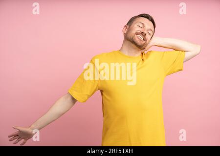 Heureux homme bien reposé s'étirant souriant après une bonne position de repos isolé sur fond rose. Banque D'Images