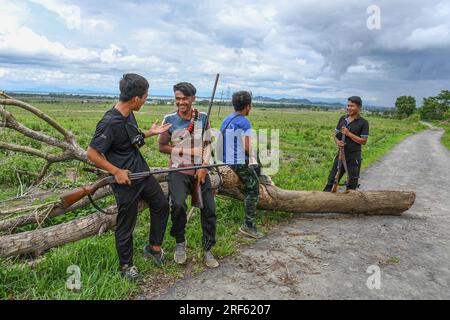 Churachandpur, Inde. 21 juin 2023. Des jeunes du village de Khousabung partagent des moments de lumière alors qu’ils montent la garde au poste de contrôle de Kangvai près de la frontière indo-birmane à Churachandpur, Manipur. Le district de Churachandpur et toute la région de la colline abritent de nombreuses tribus qui sont majoritairement chrétiennes. Ces jeunes, qui prennent la responsabilité de l’autodéfense, ont entre 13 et la trentaine et ont choisi de sacrifier leur éducation, leurs activités agricoles et leurs nuits paisibles pour protéger les frontières de leur village avec des armes et des armes. Crédit : SOPA Images Limited/Alamy Live News Banque D'Images